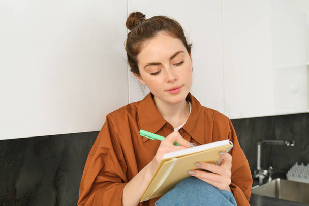Portret van een vrouw die tekent in een notitieboekje en haar gedachten opschrijft op papier. - Foto, afbeelding