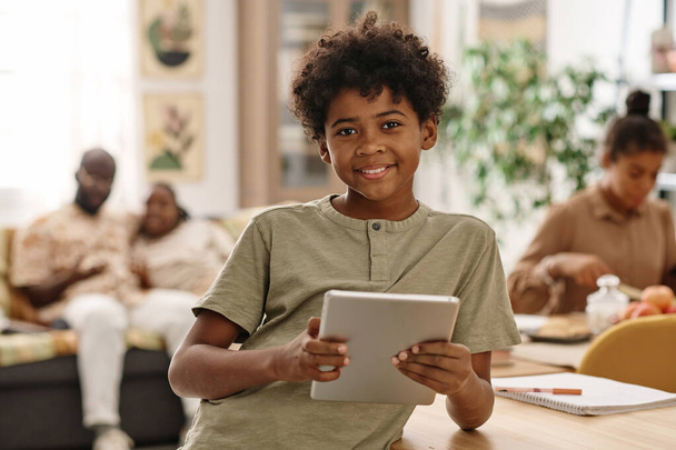 Retrato de niño negro alegre con tablet PC pasar fin de semana en casa - Foto, imagen