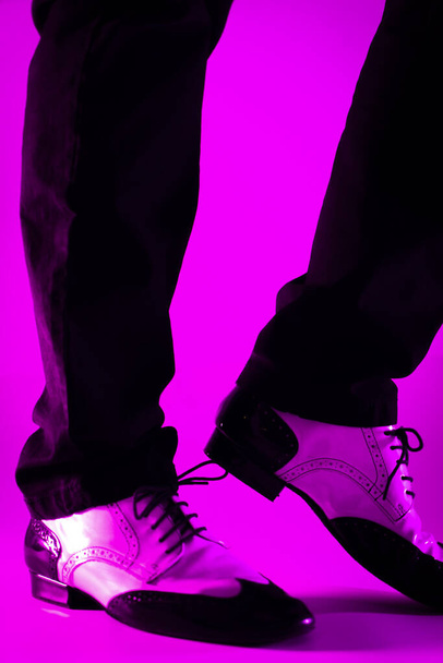 Αντρας χορευτής χορεύει σε τζαζ λάτιν παπούτσια αίθουσα χορού με φόντο απλό χρώμα - Φωτογραφία, εικόνα