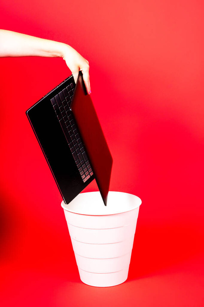 laptop preto em uma lixeira no fundo vermelho isolado - Foto, Imagem