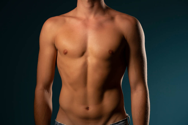 el torso de un joven atlético. concepto: el cuerpo masculino después del ejercicio y la dieta. salud de los hombres: senos afeitados sobre un fondo oscuro estudio - Foto, imagen