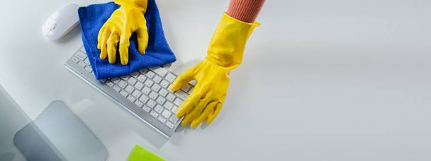 Cleaning staff wiping down office equipment, Wipe the keyboard clean with a towel and sanitizer, Wear rubber gloves when working with cleaning chemicals, cleaning idea. - Photo, Image