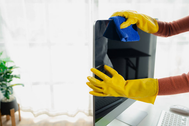 Janitor cleaning the office, Clean the monitor with a rag, wear gloves and wipe with a towel, Wear rubber gloves when working with cleaning chemicals, cleaning idea. - Photo, Image