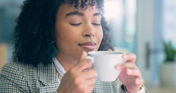 Drink, tea and black woman relax in the office on breathing in aroma on coffee break with peace and happiness in workplace. Happy, employee or drinking hot chocolate, beverage and espresso latte. - Photo, Image