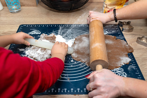 Les enfants font de la pâte à pain d'épice à l'aide d'un rouleau en bois et en plastique. - Photo, image