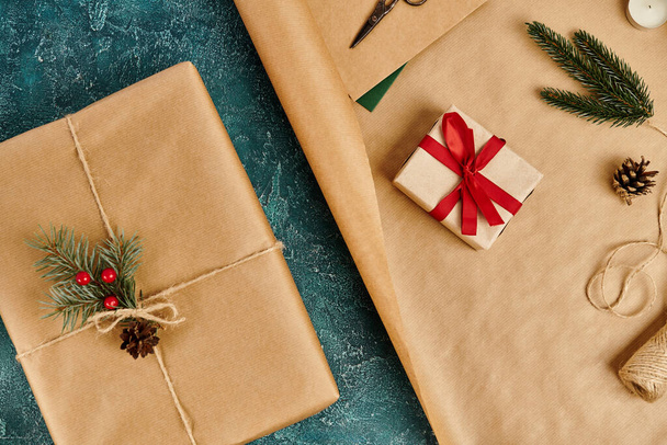 Geschenk-Boxen und Kiefer-Dekor mit Bindfaden auf Packpapier auf blau strukturiertem Hintergrund, Festthema - Foto, Bild