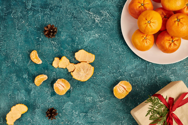 scatola regalo decorata e mandarini vicino pigne su sfondo blu strutturato, Natale still life - Foto, immagini