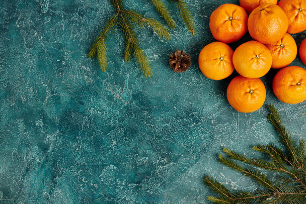 rijpe mandarijnen en sparren takken met dennenappel op blauwe textuur achtergrond met kopieerruimte - Foto, afbeelding