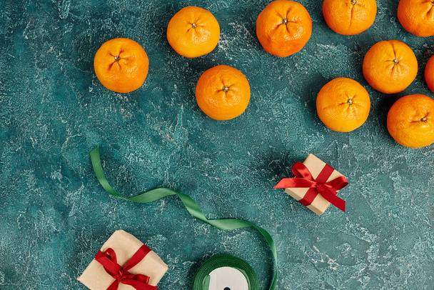 Taze mandalinaların yanında süslü hediye kutuları ve mavi desenli yüzey üzerinde kurdele, Noel natürmortu - Fotoğraf, Görsel