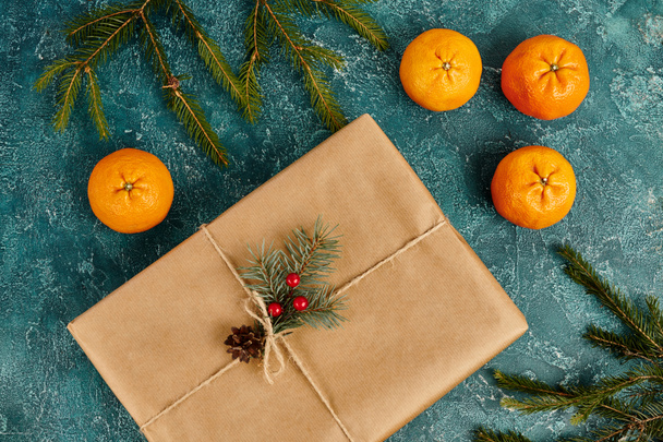 Olgun mandalların yanında süslü hediye kutusu ve mavi desenli arkaplanda çam dalları, Noel teması - Fotoğraf, Görsel