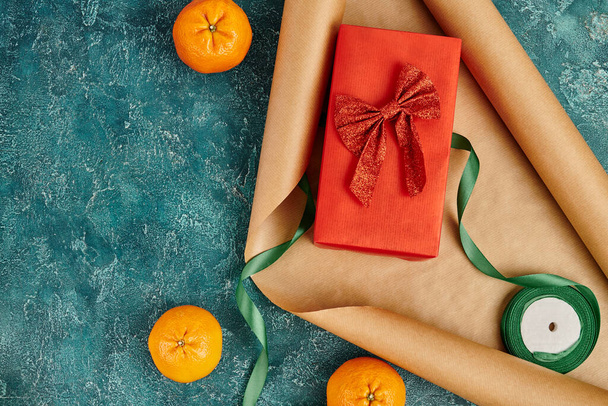 lahjapaketti punainen nauha lähellä veneet paperi ja mandariinit sininen kuvioitu pinta, joulun teema - Valokuva, kuva