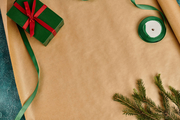 パインブランチ近くの赤い弓とクラフトラッピングペーパーのリボン,クリスマスの装飾の緑のギフトボックス - 写真・画像