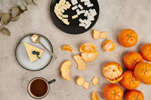 Dolcetti natalizi, budino e marshmallow vicino alla cioccolata calda sulla superficie grigia con mandarini - Foto, immagini