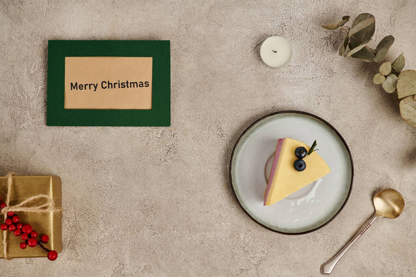 Весела різдвяна листівка біля традиційного пудингу та подарункової коробки на сірому текстурованому тлі - Фото, зображення