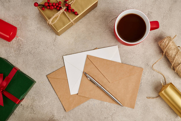 warme chocolademelk in de buurt van enveloppen en presenteren dozen met kaarsen op grijze textuur achtergrond, Kerstmis - Foto, afbeelding