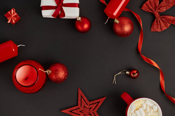 Kırmızı ve parlak Noel dekorlu çerçeve ve siyah arkaplanda marshmallowlu çikolata - Fotoğraf, Görsel