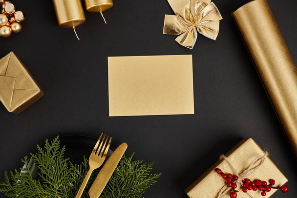 άδεια ευχετήρια κάρτα με αντίγραφο χώρο κοντά σε χρυσά μαχαιροπίρουνα και λαμπερό χριστουγεννιάτικο ντεκόρ σε μαύρο - Φωτογραφία, εικόνα