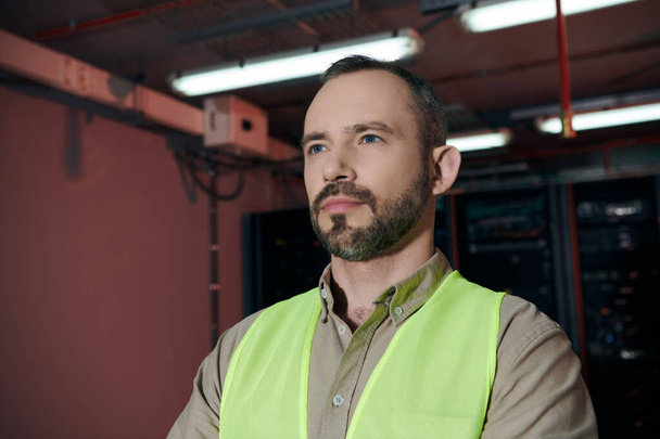 attractive pensive specialist in safety vest posing and looking away while working in data center - Photo, Image
