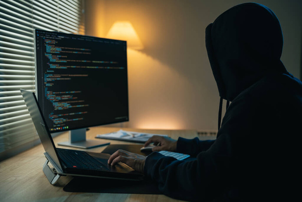 Hacker férfi csuklyát visel, kódokat ír, hogy feltörje a biztonsági rendszert. Veszélyes csuklyás hacker betör a kormányzati adatszerverekre, és megfertőzi a rendszerüket egy vírussal. Hacking és malware koncepció. - Fotó, kép