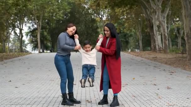 Pareja lesbiana latina jugando con su hijo en un parque. Familia LGBT. - Metraje, vídeo