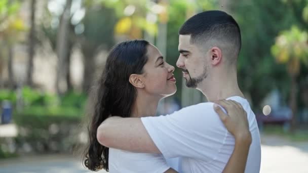 Confident, beautiful couple hugging and joyfully smiling in a sunny park, expressing love and happiness while enjoying a casual, outdoor lifestyle. - Footage, Video