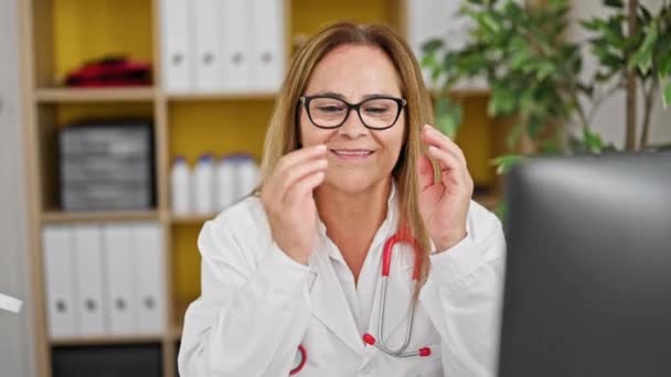 Středního věku hispánská žena lékař sundat brýle pomocí počítače na klinice - Záběry, video