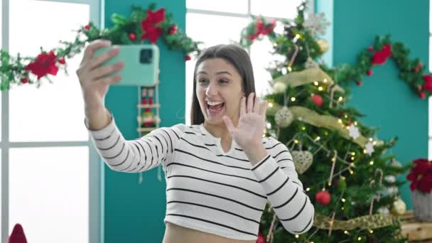 Молодая красивая латиноамериканка делает видеозвонок, размахивая рождеством дома - Кадры, видео