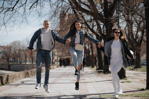 Kolme parasta ystävää nauraa hypätessään ja juostessaan puistossa kaupungissa - Valokuva, kuva