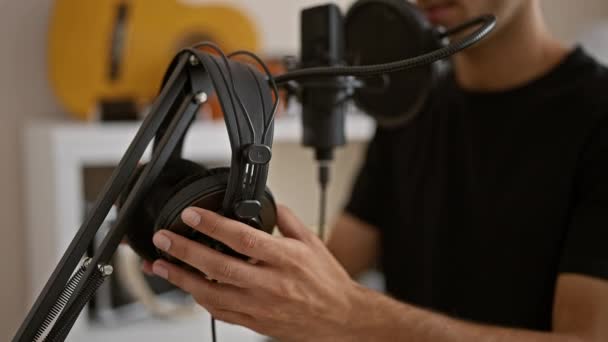 Przystojny młody Latynos, noszący słuchawki, śmiało śpiewający swoje serce w studiu muzycznym, zanurzony w melodii swojej piosenki - Materiał filmowy, wideo