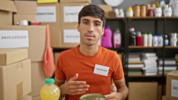 Retrato de corazón, joven y sonriente hombre hispano, manos en el corazón, voluntariado en el centro de caridad, sentado en la mesa en la sala de la comunidad - Metraje, vídeo