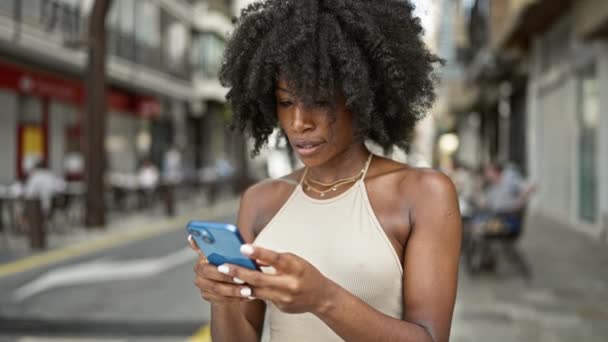African american woman using smartphone celebrating at street - Footage, Video