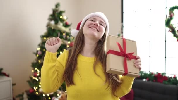 Fiatal szőke nő kezében ajándék áll karácsonyfa otthon - Felvétel, videó