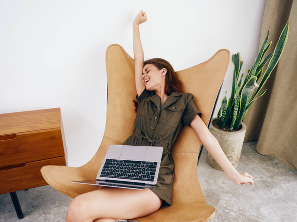 Mulher sentada em uma cadeira com um laptop em casa belo sorriso e relaxamento, moderno estilo de vida escandinavo interior elegante, espaço de cópia. Foto de alta qualidade - Foto, Imagem