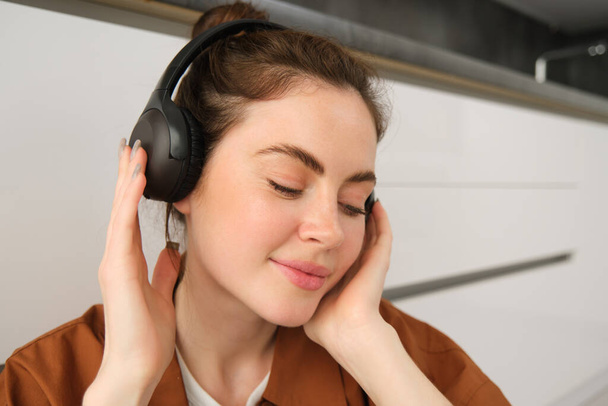 Крупним планом знімок сучасної стильної жінки в навушниках, розслабляється, слухаючи музику в бездротових навушниках. - Фото, зображення