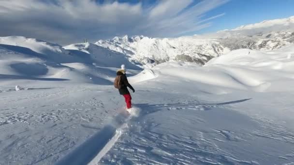 Авантюристка фрирайд сноуборд на свежем порошковом снегу в Джулианских Альпах. Леди свернула с лыжного склона, чтобы насладиться некоторыми поворотами на нетронутом снегу. Прекрасный солнечный зимний день для езды на сноуборде. - Кадры, видео