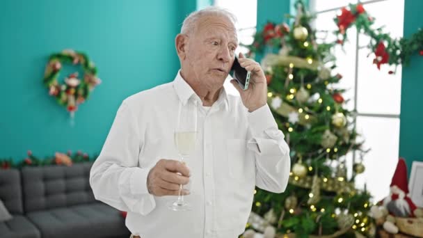 Yaşlı gri saçlı adam akıllı telefondan konuşuyor evde elinde şampanya kadehiyle Noel 'i kutluyor. - Video, Çekim