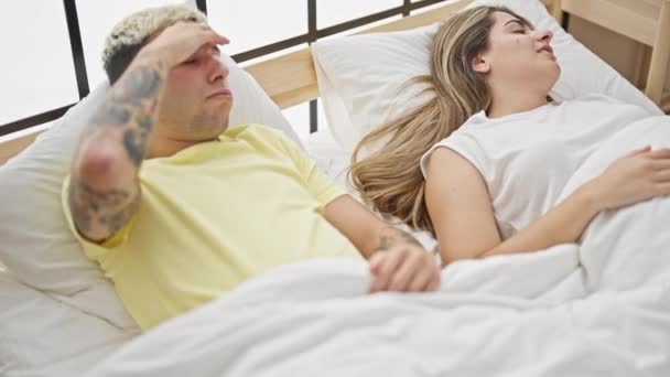 Piękna para cierpiąca na bezsenność za chrapanie leżące na łóżku w sypialni - Materiał filmowy, wideo