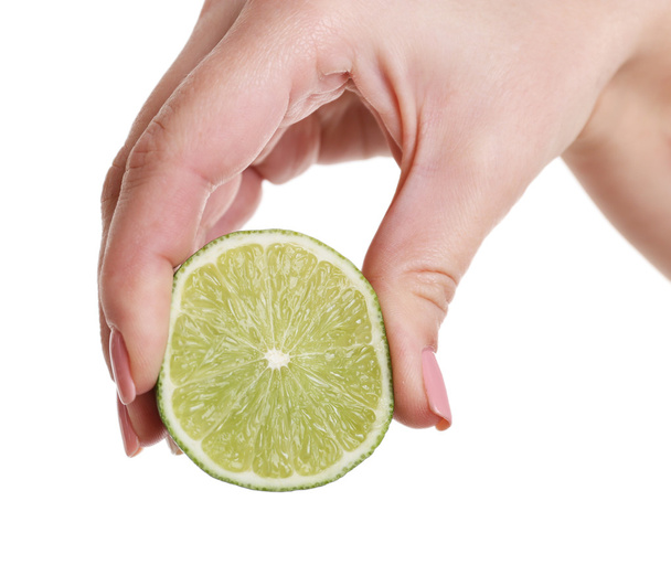 Female hand squeezing lime isolated on white - Φωτογραφία, εικόνα