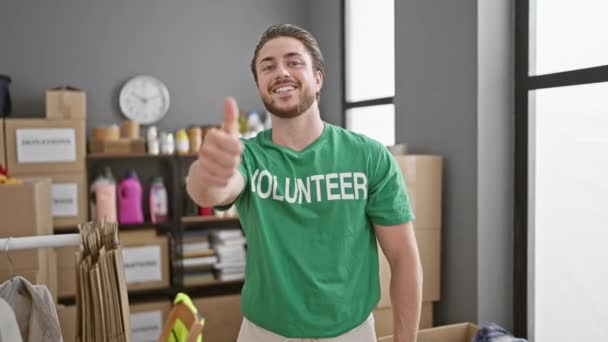 Jonge Spaanse man vrijwilliger doet duim omhoog gebaar glimlachend naar liefdadigheidscentrum - Video