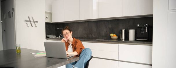 Muotokuva naisesta freelancer, ohjelmoija työskentelee kotoa. Nainen opiskelija tai yrityksen omistaja istuu kannettavan keittiössä. - Valokuva, kuva