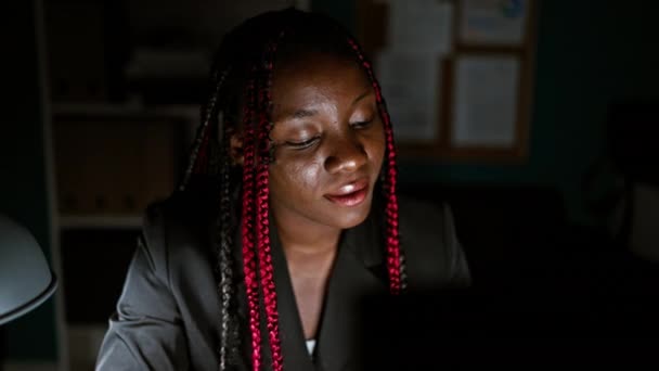 Улыбающаяся африканская американская бизнесвумен наслаждается своей работой, уверенно пользуясь компьютером в офисе - Кадры, видео