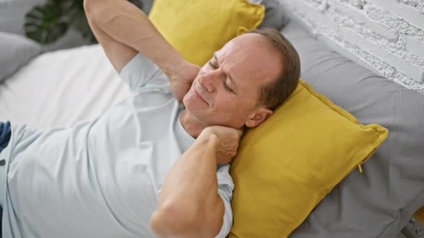 Hombre infeliz de mediana edad, gravemente herido, dolor cervical duradero, acostado en la cama, sufriendo en silencio dentro de la soledad de su dormitorio - Metraje, vídeo