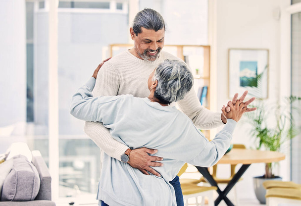 Ηλικιωμένο ζευγάρι, αγκαλιάστε και κρατήστε τα χέρια στο χορό για την αγάπη, φροντίδα ή συγκόλληση μαζί στο σαλόνι στο σπίτι. Χαρούμενος ηλικιωμένος άνδρας και γυναίκα που απολαμβάνει ποιοτικό χρόνο, συνταξιοδότηση ή γιορτή για την επέτειο. - Φωτογραφία, εικόνα