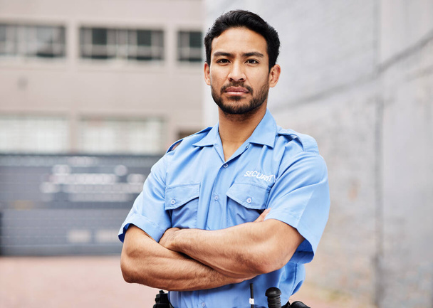 Portré, férfi és biztonsági őr, keresztbe tett karokkal a rendőrség, a védelem és a biztonság érdekében a városban. Bűnüldözés, testőr és komoly ázsiai férfi tiszt kék egyenruhában kültéri járőrözésre.. - Fotó, kép