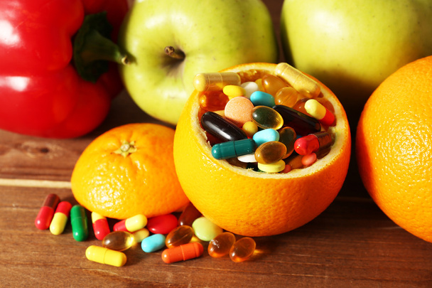 Orange fruit filled colorful pills, on wooden background - Fotó, kép