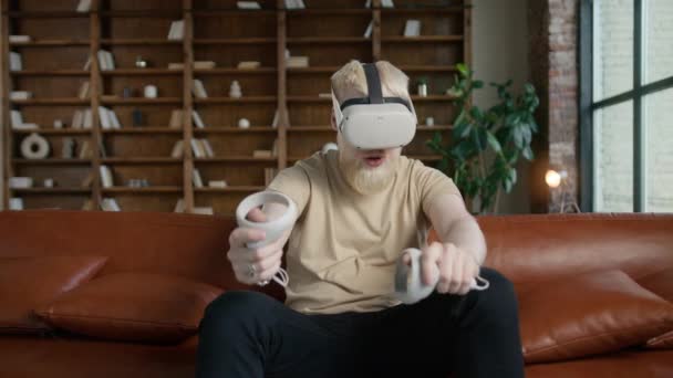 Cyber gamer in VR occhiali gioca gioco di realtà virtuale in moderno loft spazio appartamento in stile. Hipster barbuto ragazzo concetto di gioco. Giovane bell'uomo si guarda intorno e spara pistola virtuale utilizzando joystick - Filmati, video