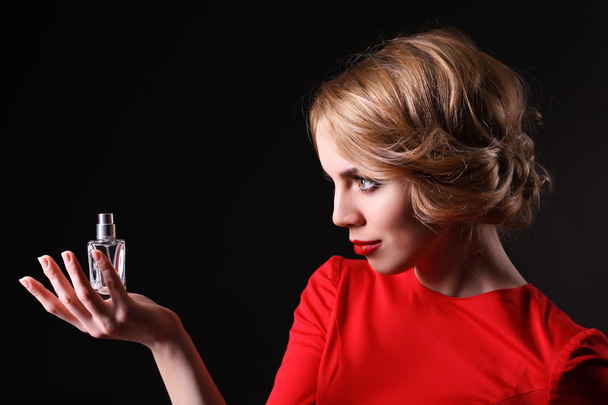 Beautiful young woman with perfume bottle on black background - Foto, imagen