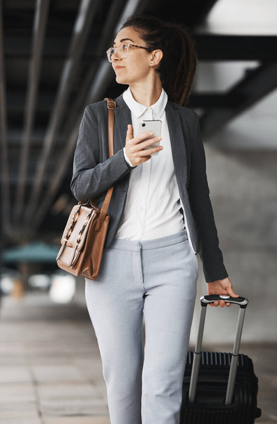 Telefon, Vision und Koffer mit einer Geschäftsfrau, die auf einem Flughafen-Parkplatz in der Stadt spazieren geht. Mobil, Gepäck und Denken mit einer jungen Berufstätigen auf internationaler Arbeitsreise. - Foto, Bild