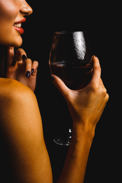 Um copo de vinho tinto nas mãos de uma mulher sexy em um vestido vermelho - Foto, Imagem
