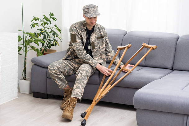 Soldat in khakifarbener Militäruniform auf Krücken. - Foto, Bild